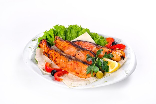 Fried fish with vegetables on a plate on a white isolated background