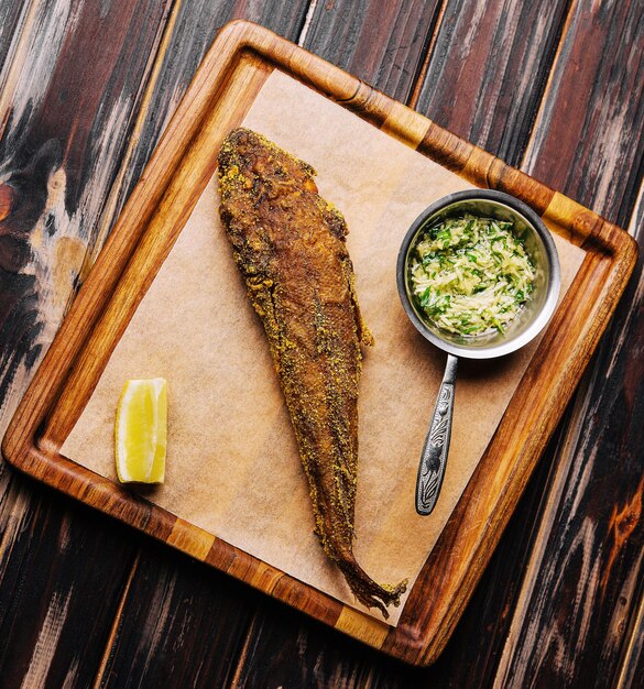 Fried fish on wooden board with spicy sauce