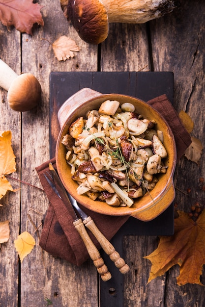 Funghi di bosco fritti, porcini, cipolle. piatto rustico in una padella, alimento vegetariano di autunno in cima alla vista