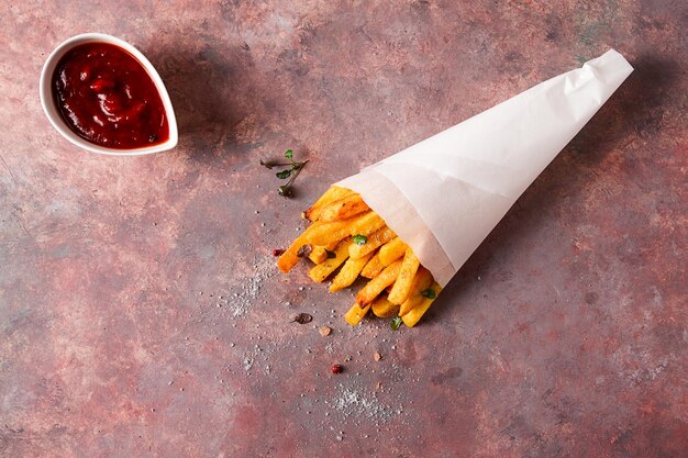 Fried French fries in a paper bag on an abstract background no people rustic