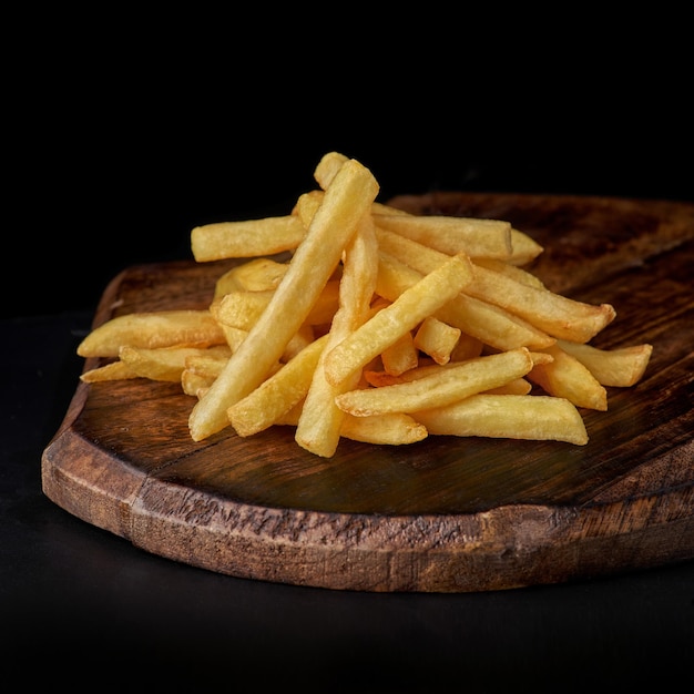 Fried French fries potatoes with salt in kitchen tray Wooden background Copy space