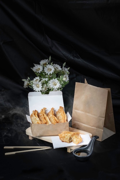 Fried Gyoza, hot fries in a smoked cardboard box, black background.