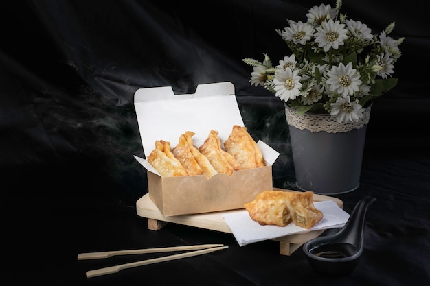 Fried Gyoza, warme frietjes in een gerookte kartonnen doos, zwarte achtergrond.