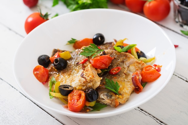 Fried hake fillet with tomato and olives in the Mediterranean style