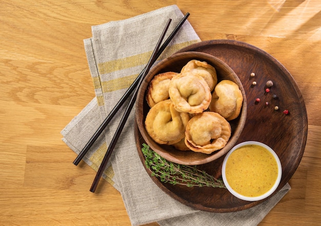 Fried homemade dumplings with meat curry sauce and thyme on a wooden table
