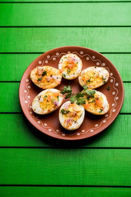 Fried hot boiled egg masala is a popular healthy breakfast or starter menu from India. With onion, coriander, black pepper, tomato and salt sprinkled over half of eggs