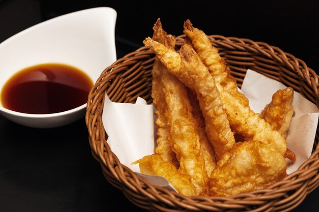 Fried king prawns in batter in a wicker basket on a black background