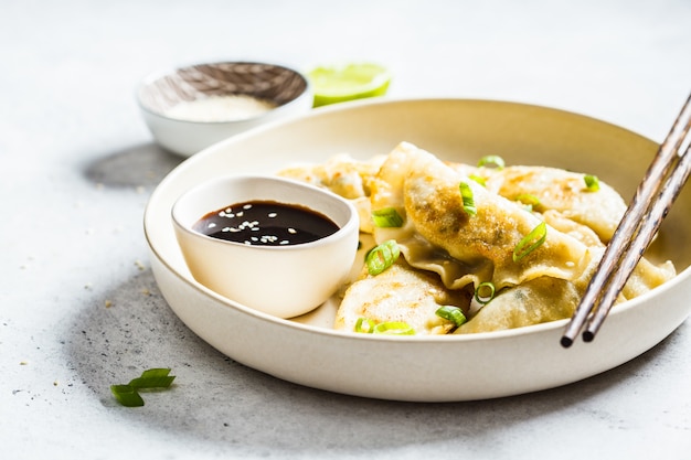 Fried Korean-bollen met groene ui en saus op witte plaat.