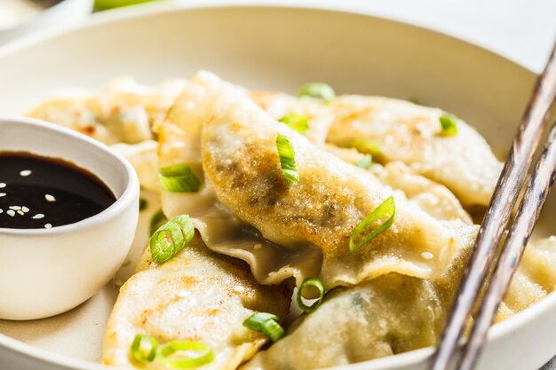 Fried Korean-bollen met groene ui en saus op witte plaat.