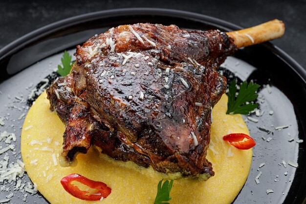 Fried leg of lamb with garnish and pepper on a dark background