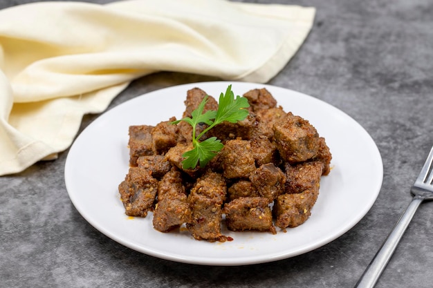 Photo fried liver cubes on a dark background turkish traditional food arnavut cigeri horizontal view close up