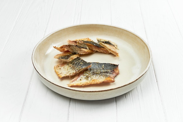 Fried mackerel in a plate on a white wooden background