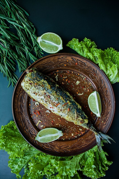 魚と野菜の調味料を皿に揚げサバ。暗い背景トップビュー。