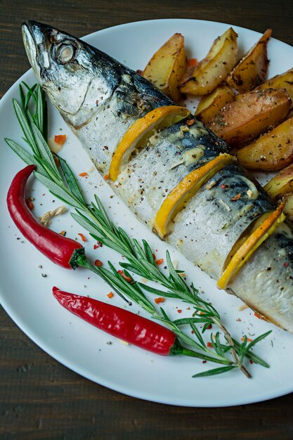 Fried mackerel served on a plate, decorated with spices, herbs and vegetables. Proper nutrition.