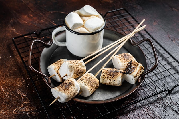 Fried Marshmallow on the sticks with Cup of coffee Dark background Top view