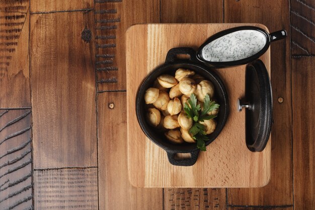 Foto gnocchi di carne fritti pelmeni, chuchpara in padella nera. fondo in legno.