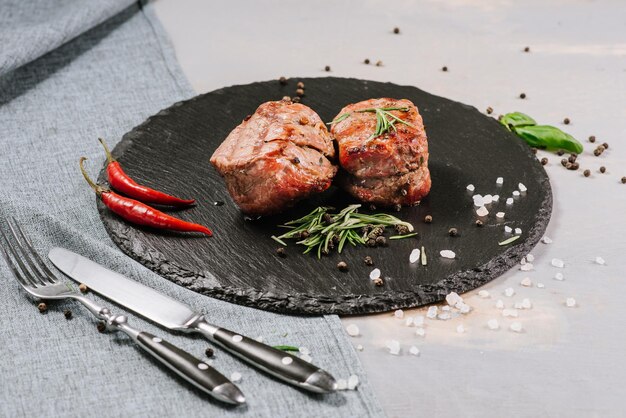 Fried meat medallions with spices on the wooden background