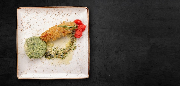 Fried meat roll in breadcrumbs in a plate on a dark concrete background