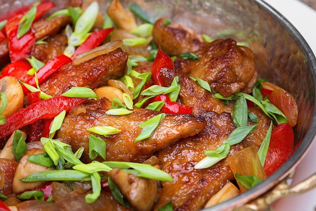 Fried meat with vegetables green onions and mushrooms closeup