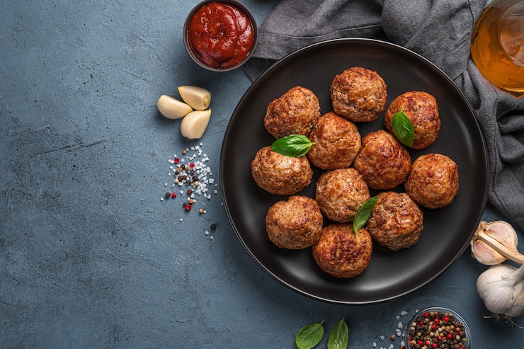 Photo fried meatballs with basil on a dark background with tomato sauce and garlic. top view, copy space.