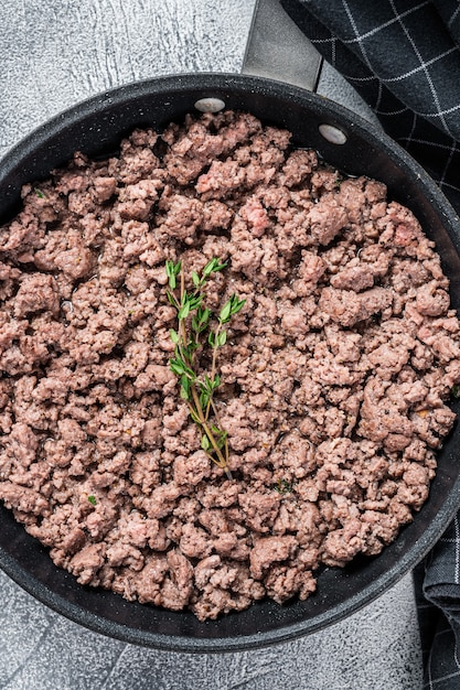 Fried mince beef and lamb meat in a pan with herbs. White background. Top view.