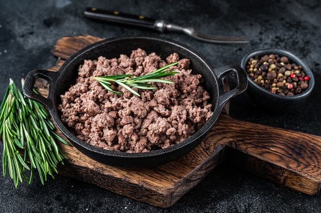 Fried mince beef meat in a pan for cooking pasta. black background. top view.