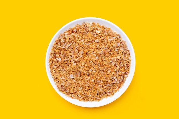 Fried minced garlic recipe in white plate on yellow background.