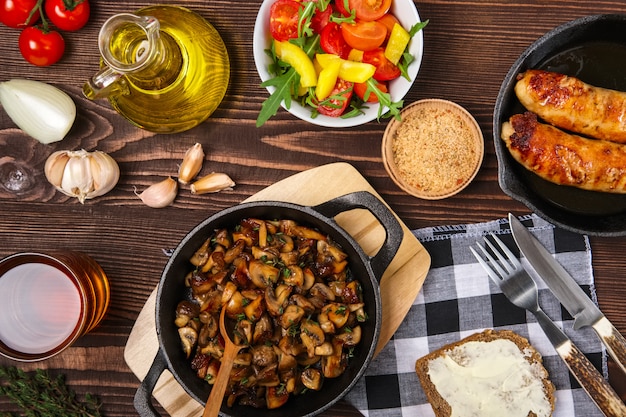 Fried mushrooms and sausage in cas-iron skillet. Ingredients for rustic simple food, view from above.