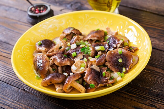 Fried mushrooms shiitake with green onion on wooden background. Chinese food.