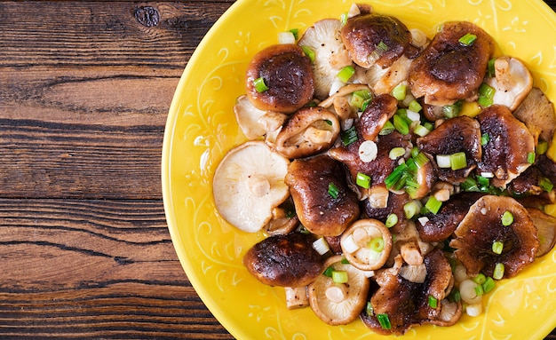 Fried mushrooms shiitake with green onion on wooden table. Chinese food.Top view. Flat lay