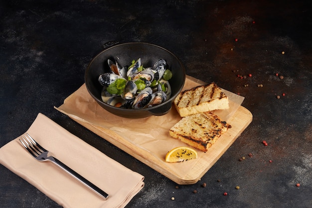 Fried mussels with bread slice, dark background