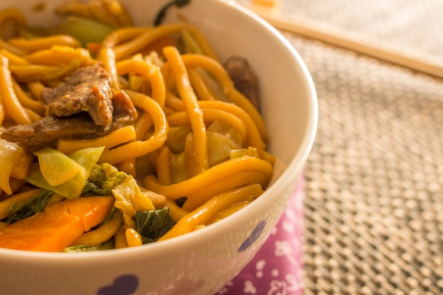 Fried noodle. Yakisoba with beef, chicken and vegetables in a white bowl. 