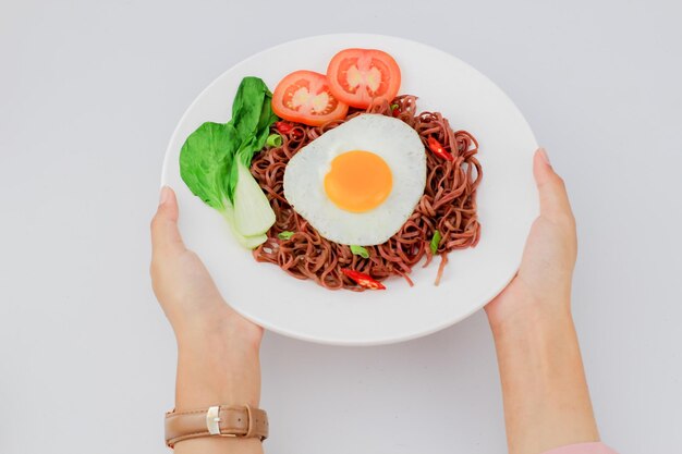 Fried noodles served with fried eggs and vegetables on a plate