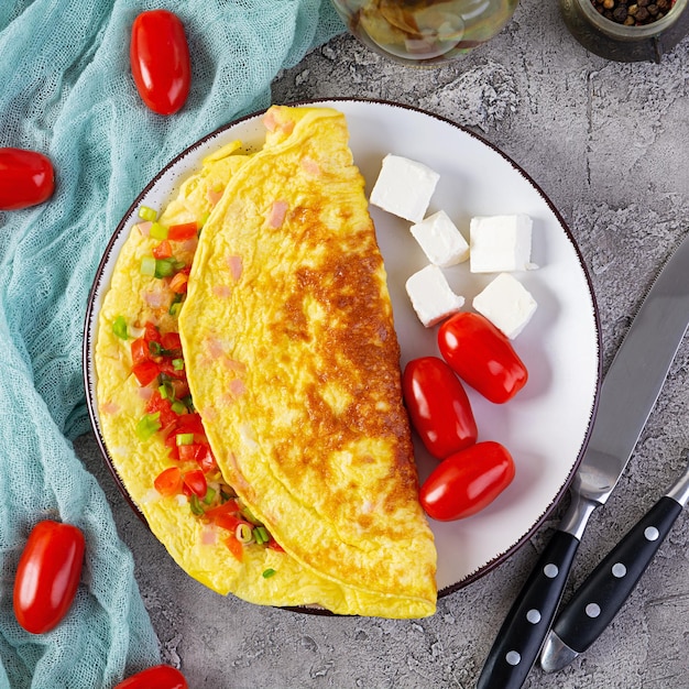 Жареный омлет с говядиной, помидорами, луком и зеленью. Вкусный завтрак с яичницей. Вид сверху