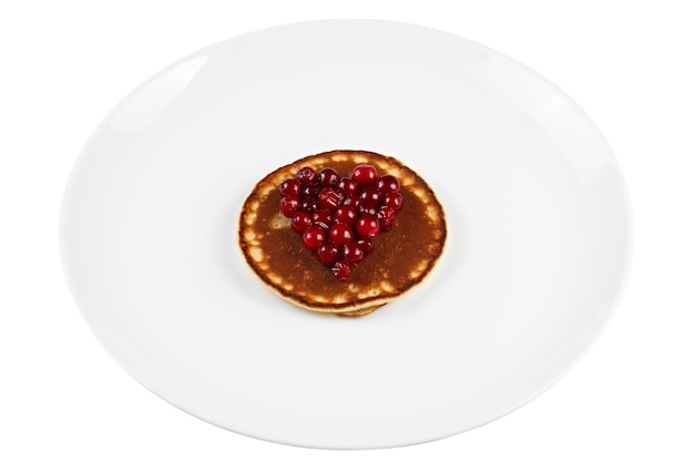Fried pancakes with cranberry heart shaped with honey on a plate, isolated.