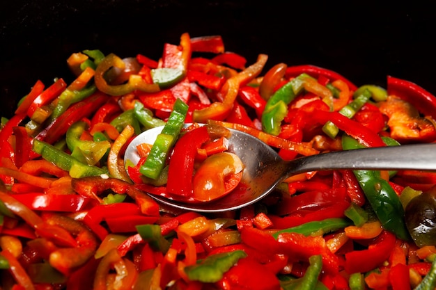 Foto primo piano del processo di cottura delle verdure dei peperoni fritti fette multicolori