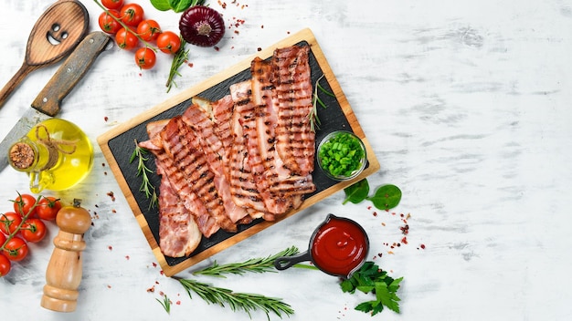 Fried pieces of bacon on a black stone board Top view Free space for text