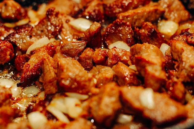 Fried pieces of meat with onions and seasonings in a frying pan closeup meat goulash