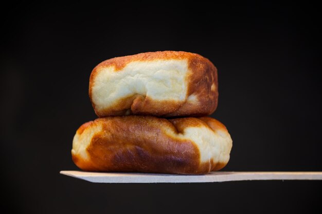 Fried pies filled with yeast dough on a wooden paddle isolated on a black background Ukrainian food