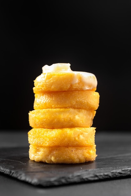 Fried polenta on a blackened background with macarella cheese side view vertical shot