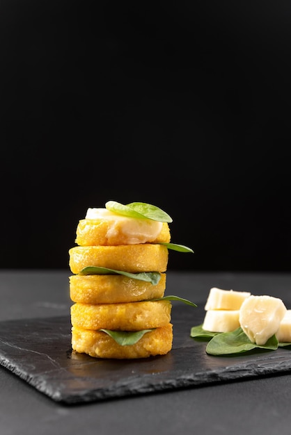 Fried polenta on a blackened background with macarella cheese side view with blank space for text