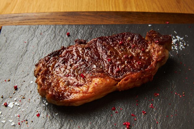 Fried pork chop lies on a black board closeup