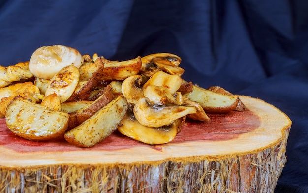 Fried potato with mushrooms in on wooden background