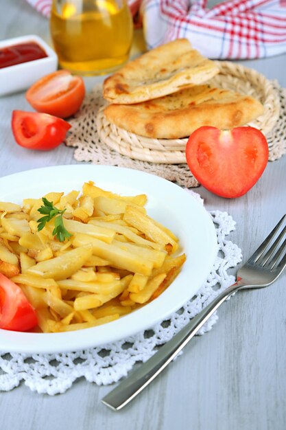 Fried potatoes on plate on wooden table closeup