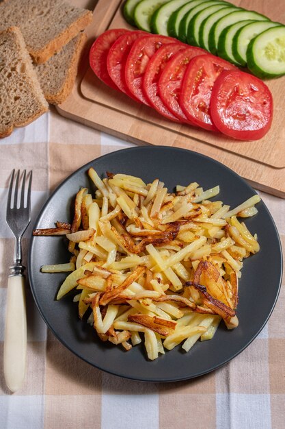 Fried potatoes with a crispy crust with bread and chopped vegetables top view