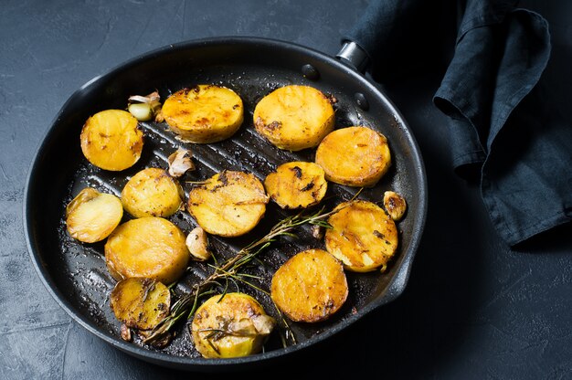 Fried potatoes with garlic and rosemary in a frying pan.