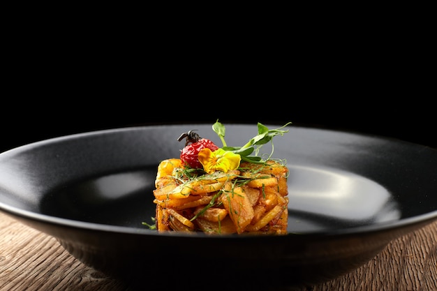 Fried potatoes with herbs on a black plate