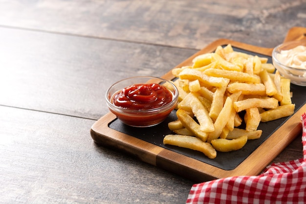 Fried potatoes with ketchup and Mayonnaise on wooden tablexA