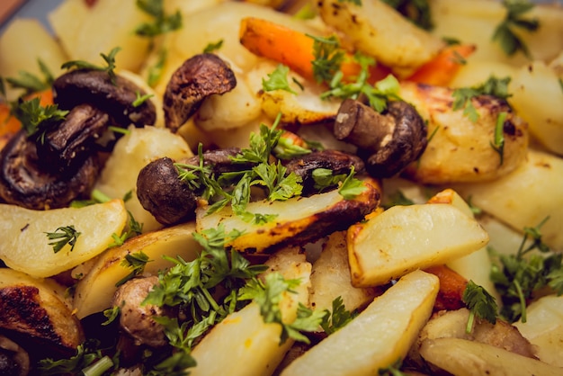 Patate fritte con i funghi sul piatto bianco.