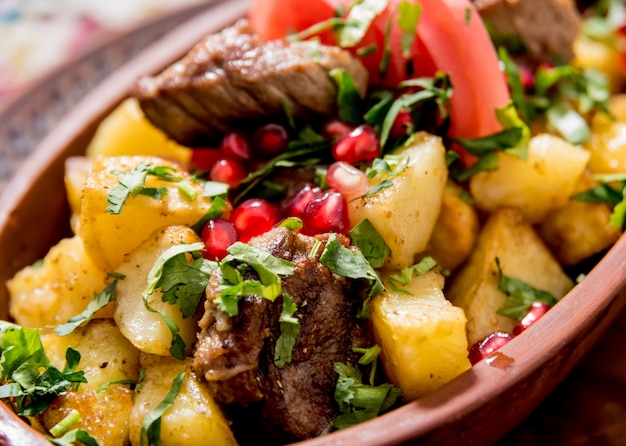 Fried potatoes with pieces of meat in a clay pot. European cuisine.